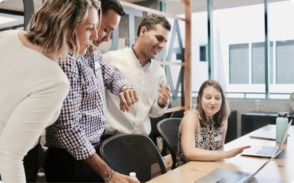 Colleagues gathered around a laptop in an office